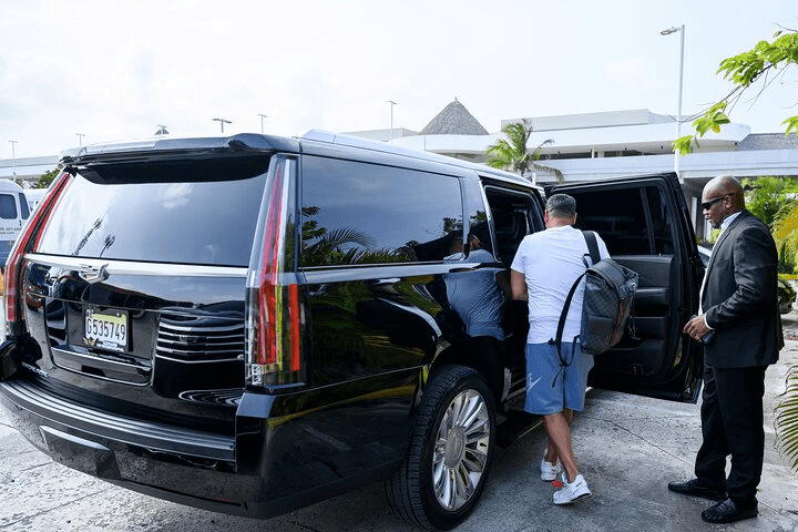 Man getting into a black SUV with a driver holding the door open.